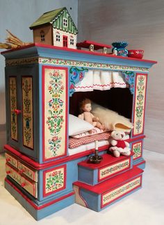 a doll house with a bed, dresser and teddy bear on the bottom shelf next to it