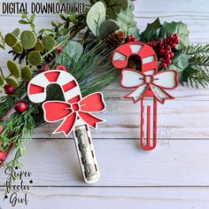 two christmas decorations are sitting next to each other on a white wooden surface with greenery and pine cones