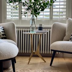 a living room with two chairs and a table in front of a radiator