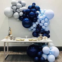 a table topped with blue and white balloons