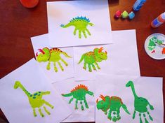 four children's handprints are displayed on paper with dinosaurs drawn on them