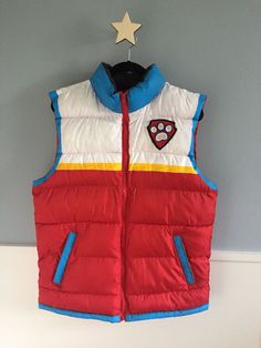 a red and white vest hanging on a wall next to a stuffed animal bear toy