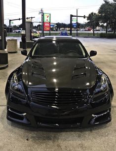 a black sports car parked in front of a gas station with no one around it