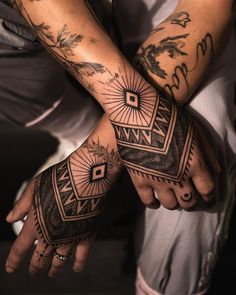 two people with tattoos on their arms and hands are holding each other's hands