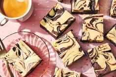 some brownies are on a pink plate next to a cup of coffee