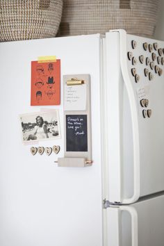 a white refrigerator with magnets and pictures on the door, next to a basket