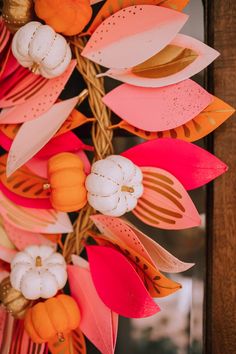 a wreath decorated with paper flowers and pumpkins