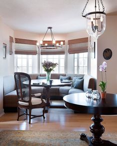 a living room filled with furniture and a chandelier hanging from the ceiling next to a window