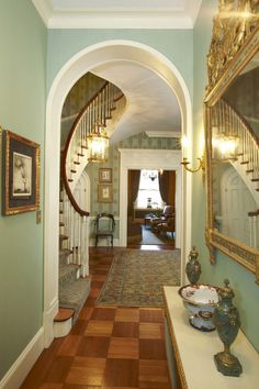 the hallway is decorated in green and gold with an archway leading up to the second floor