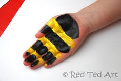 a child's hand with yellow and black paint on it