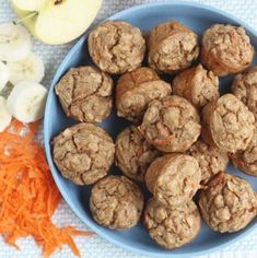 a blue bowl filled with meatballs next to carrots and an onion on a table