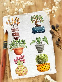 a piece of paper with potted plants on it next to a brush and flowers