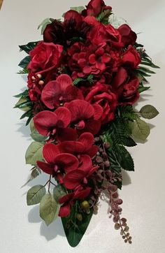 a bouquet of red flowers and greenery on a table