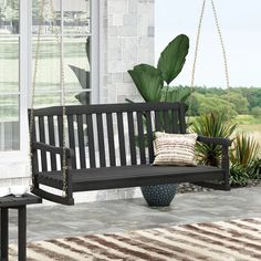 a porch swing sitting next to a potted plant