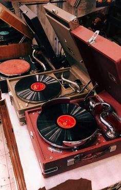 two turntables sitting on top of suitcases in a room filled with old records