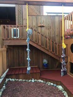 there is a wooden deck with ropes on it and a swing set in the background