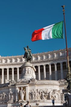 an italian flag flying in front of a building with statues on the sides and columns