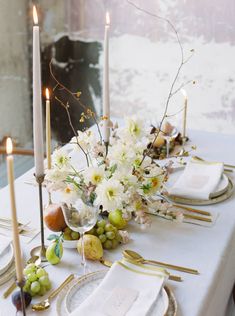 the table is set with white flowers and gold place settings, candles, and napkins