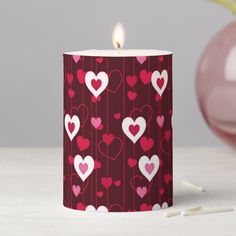 a candle with hearts on it sitting next to a pink vase filled with flowers and candles