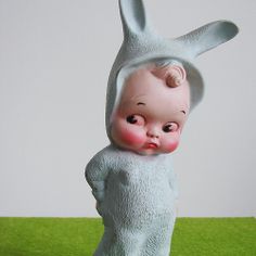 a small statue of a baby in a bunny suit on top of a green surface