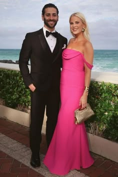 a man in a tuxedo standing next to a woman in a pink dress