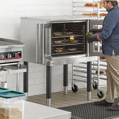 a man standing in front of an oven filled with donuts and muffins