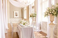 an elegant dining room with white drapes and floral centerpieces