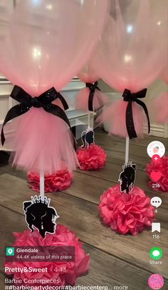 some pink and black balloons are in the air on a wooden table with other decorations