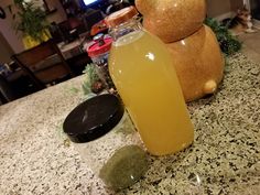 a bottle of liquid sitting on top of a counter next to a teddy bear statue