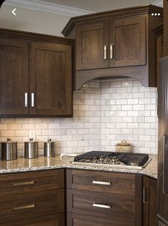 a kitchen with wooden cabinets and white tile backsplash, wood grain cabinetry