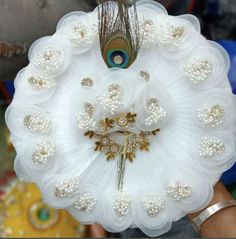 the peacock is sitting on top of the white frocked flower wreath with pearls