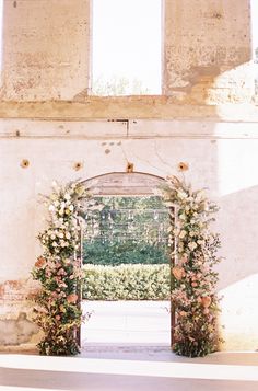 an archway is decorated with flowers and greenery