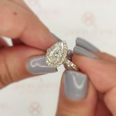 a woman's hand holding a ring with a diamond on it and the other hand