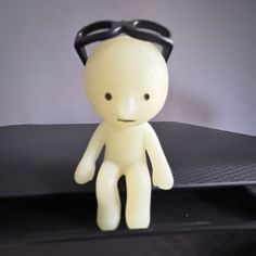 a small white doll with black glasses on it's head sitting on a table