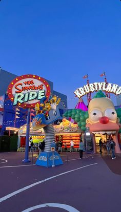 an amusement park at dusk with people walking around