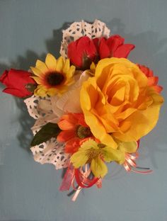 a bouquet of yellow and red flowers sitting on top of a white lace doily