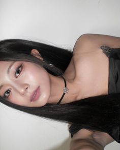 a woman with long black hair posing for the camera