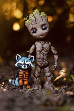 a small toy raccoon standing next to a baby groote