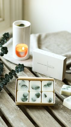 some soaps are sitting on a wooden table next to a candle and other items