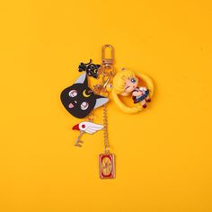 the key chain is decorated with various cartoon characters on yellow background and has a black cat