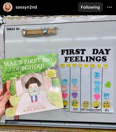 a person holding up a book in front of a white refrigerator with magnets on it