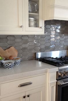 a white kitchen with stainless steel backsplash and hexagonal tiles on the wall