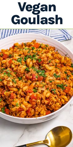 vegan goulash in a white bowl with gold spoons on the side