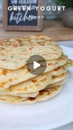 a stack of flatbreads on a white plate with a sign in the background