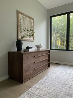 a room with a large window and a wooden dresser