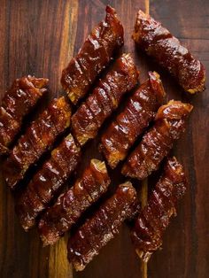 several pieces of meat are on a wooden cutting board with toothpicks in it