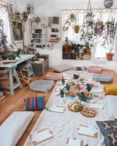 a room filled with lots of plants next to a table covered in cards and papers