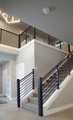 an empty room with stairs and railings leading to the second floor, which is lit by recessing lights