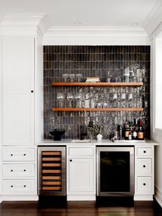 a kitchen with white cabinets and shelves filled with wine glasses