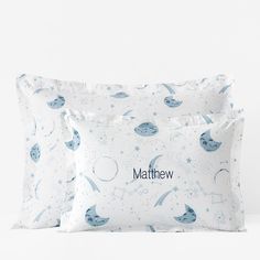 two white pillows with blue stars and planets on them, one has the word'mathew'printed on it